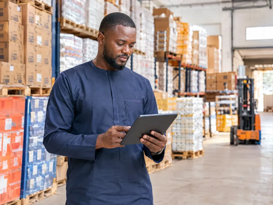 Un grossiste vérifie son stock sur une tablette dans un grand entrepôt